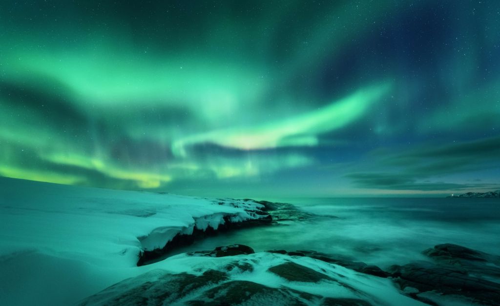 Aurora boreal verde sobre rocas nevadas