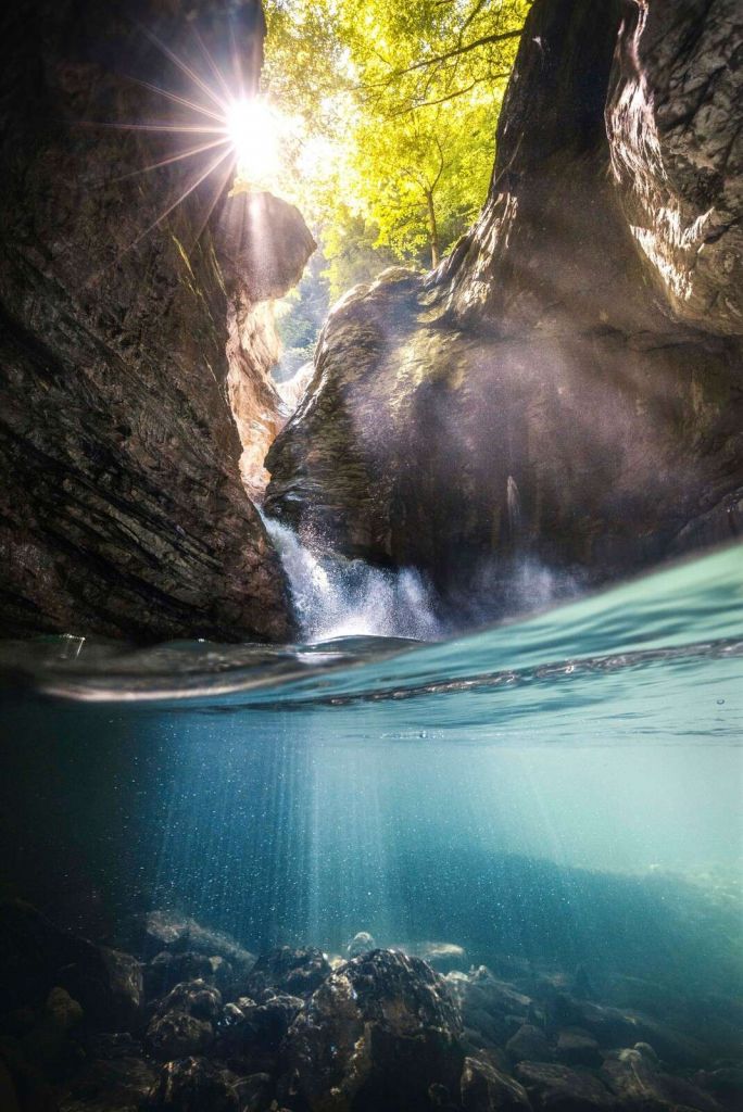 Luz del sol en un barranco de montaña con cascada.