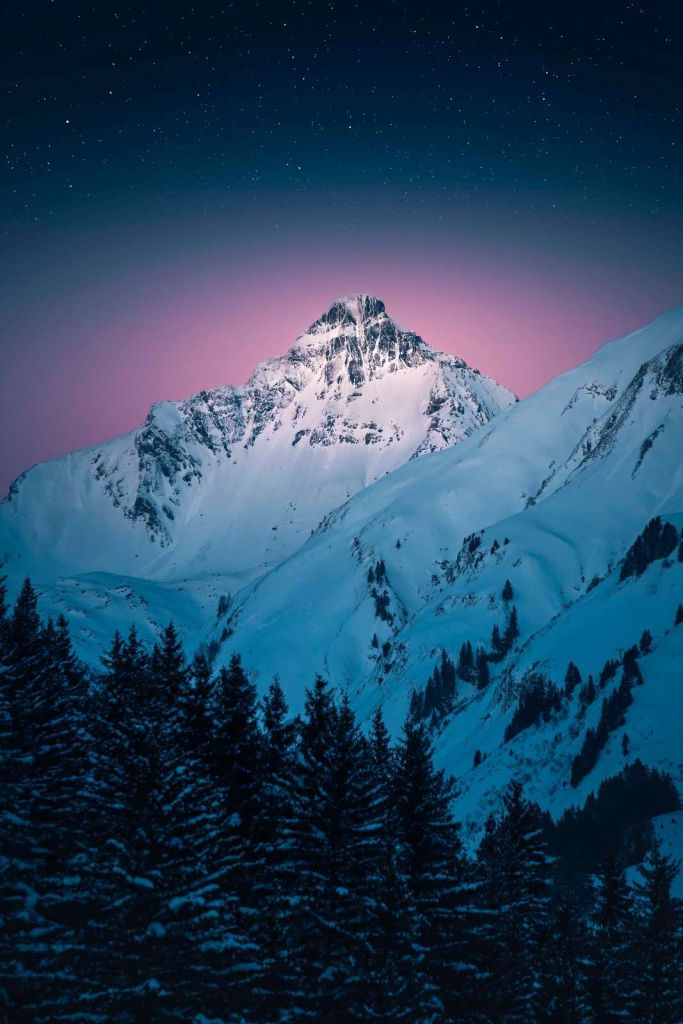 Pico de montaña nevado en una noche estrellada.