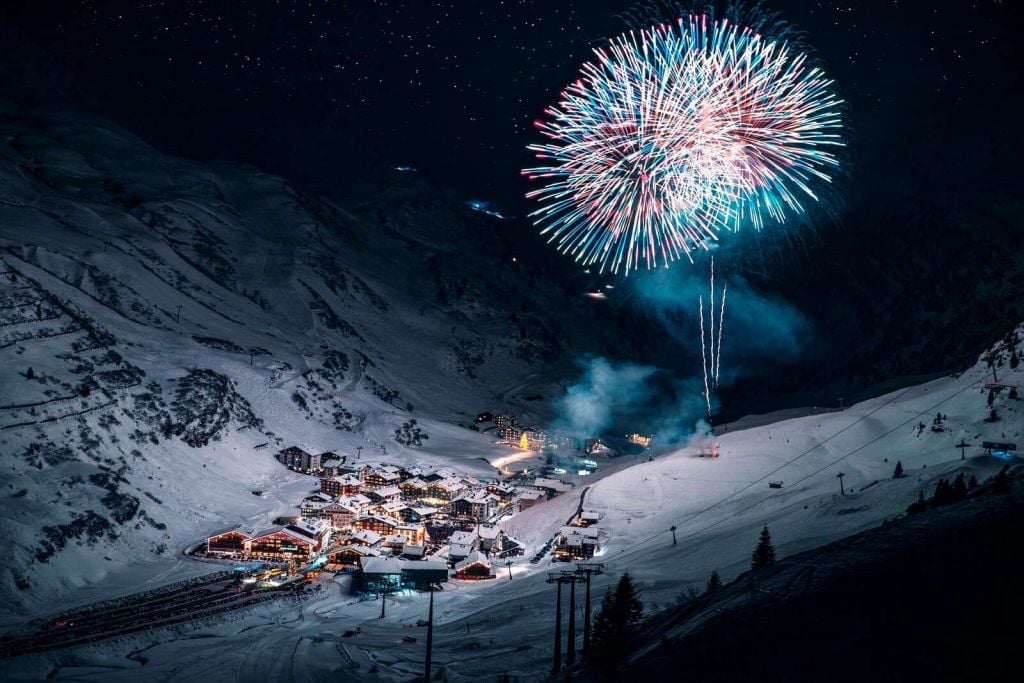 Fuegos artificiales sobre un pueblo de montaña invernal.