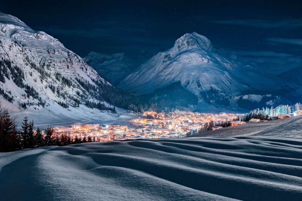 Pueblo invernal bajo la luz de la luna en un valle alpino.