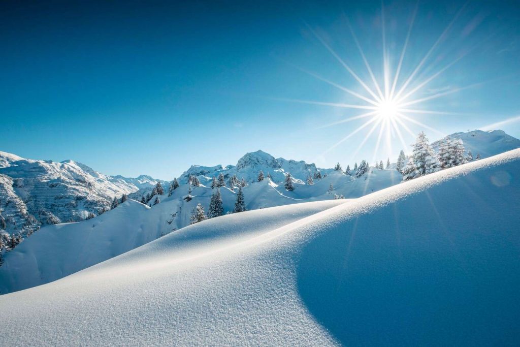 Luz del sol sobre colinas de nieve brillante.