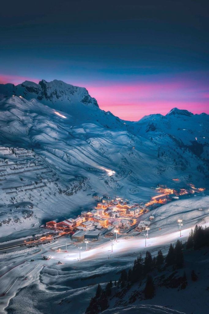 Pueblo nevado bajo cielo nocturno morado.