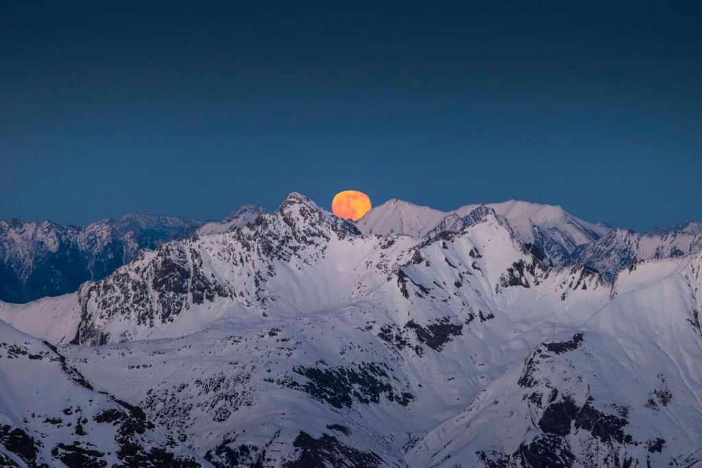 Luna llena sobre cimas alpinas.