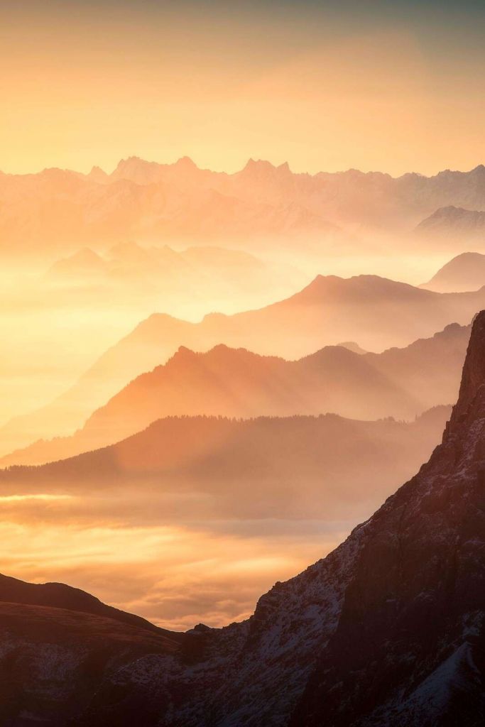 Siluetas de montañas en capas al amanecer.
