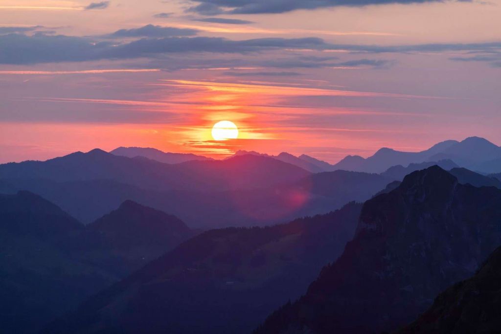 Atardecer sobre capas de montañas moradas.