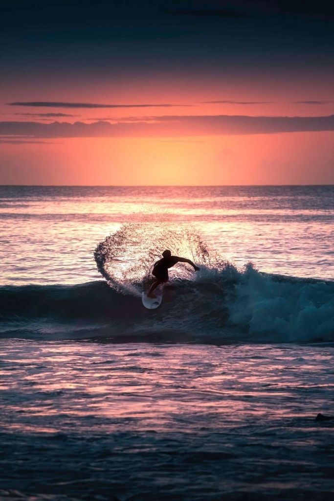 Surfista en el resplandor rosado de la tarde.