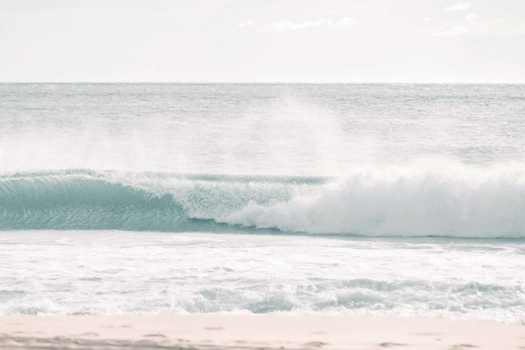 Ola rompiendo en la playa clara