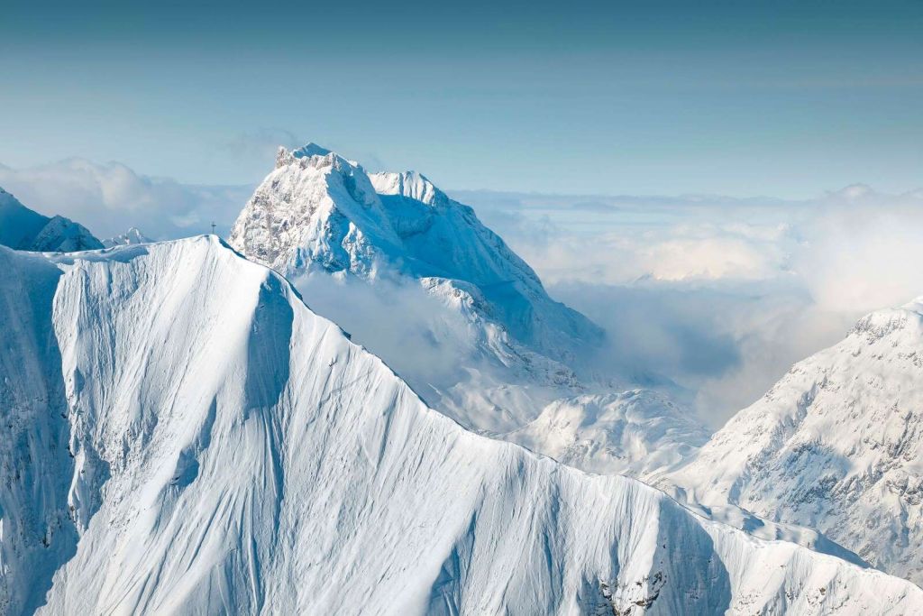 Monta√±as nevadas sobre un manto de nubes
