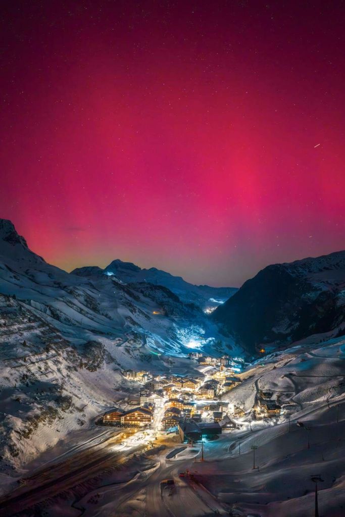 Aurora boreal rosa sobre pueblo de monta√±a