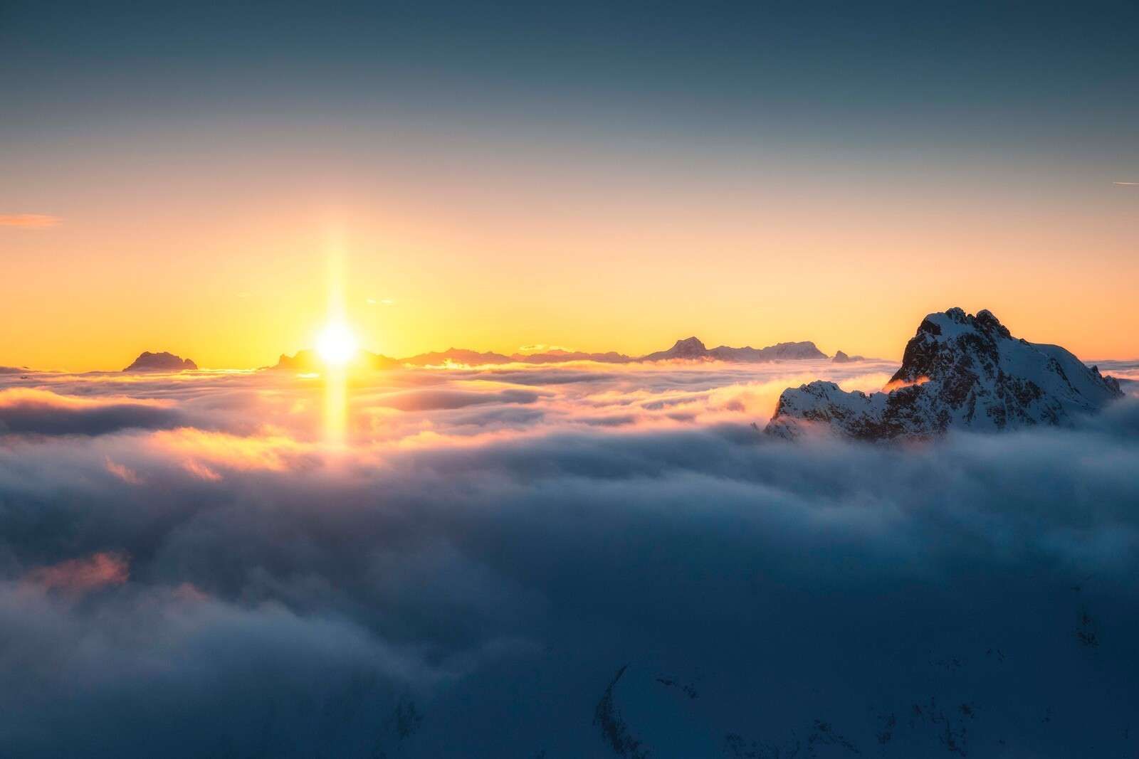 Amanecer sobre el mar de nubes y cimas de montañas.