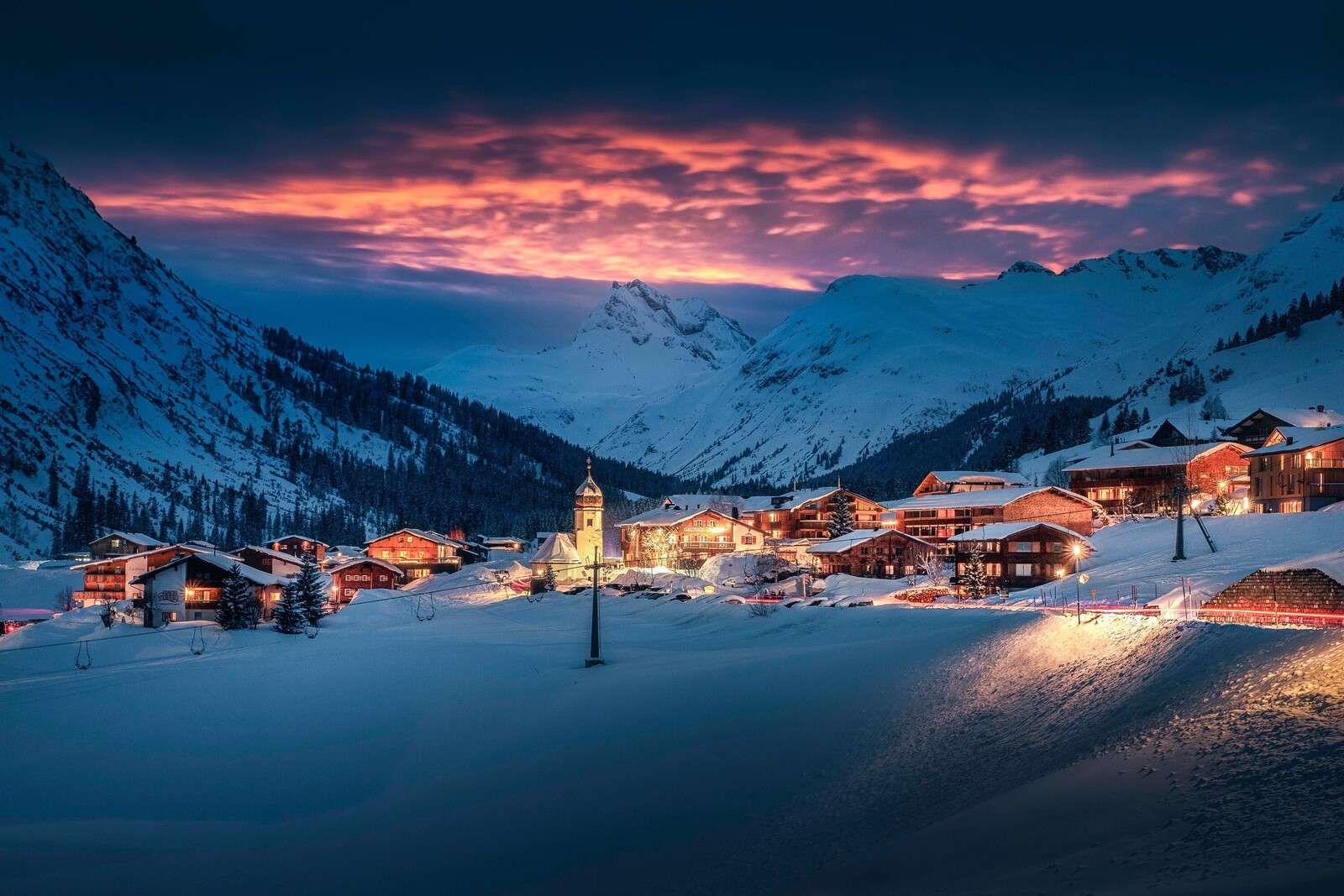 Luz de la tarde sobre un pueblo de montaña en la nieve.