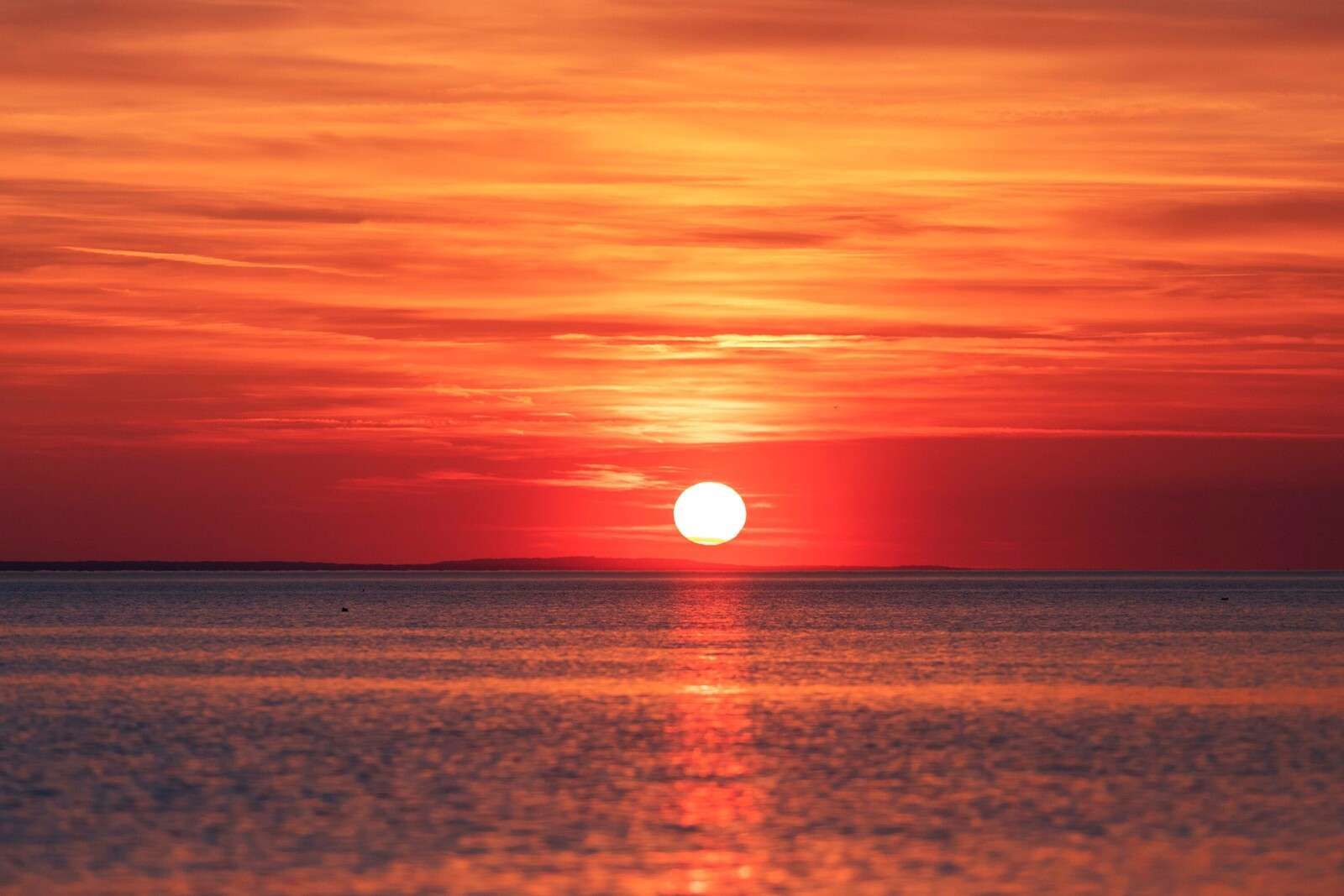 Puesta de sol roja sobre un mar tranquilo.
