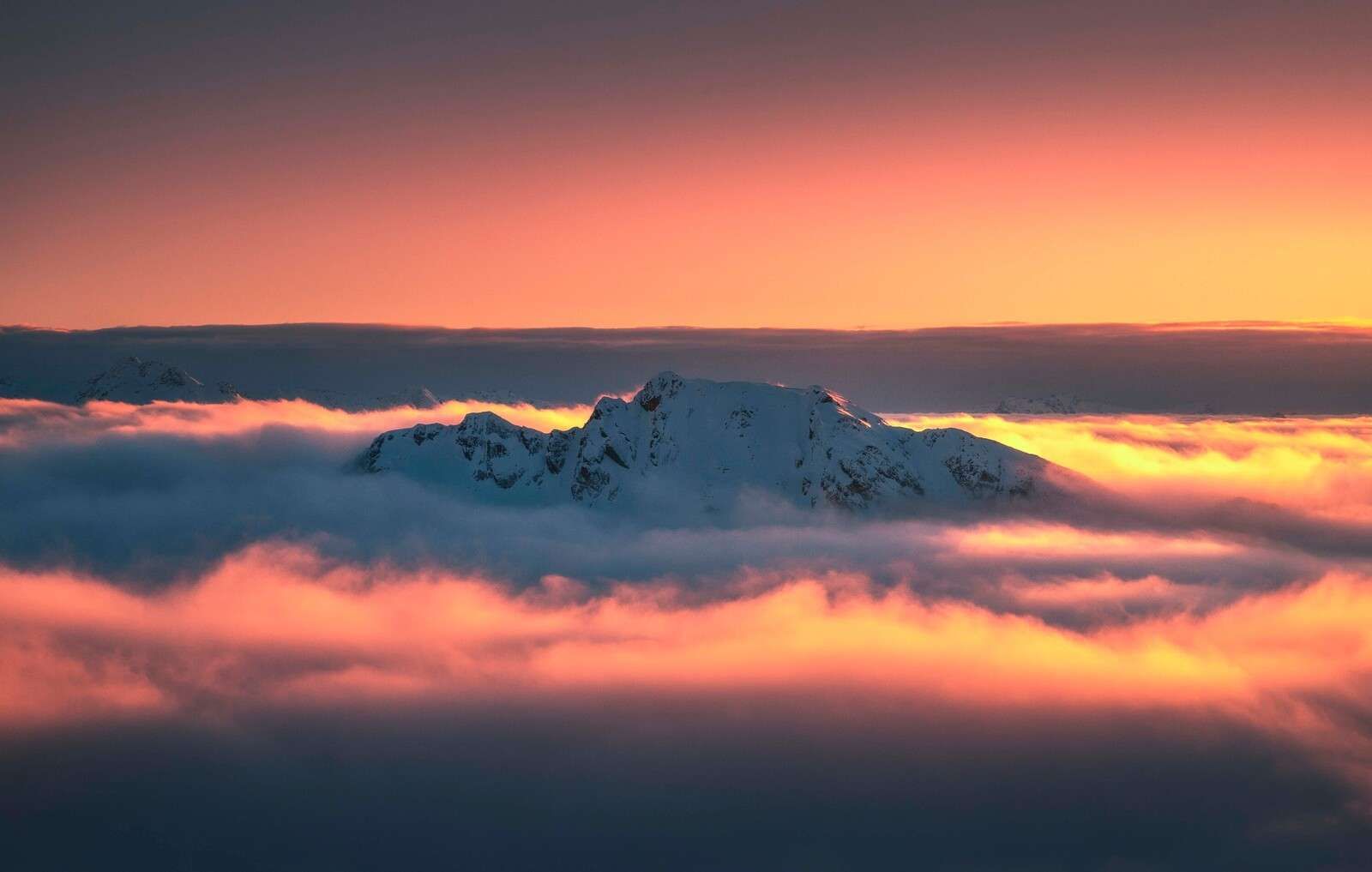 Pico de montaña nevado en un mar de nubes