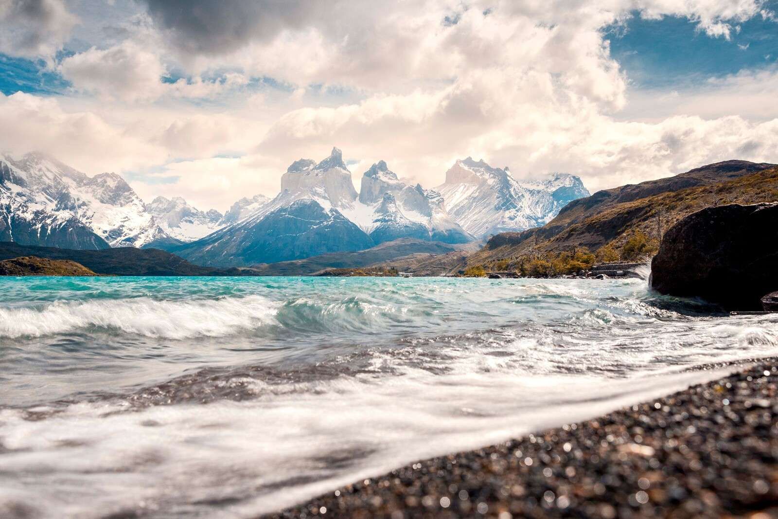 Lago de montaña turquesa con costa ondulante.