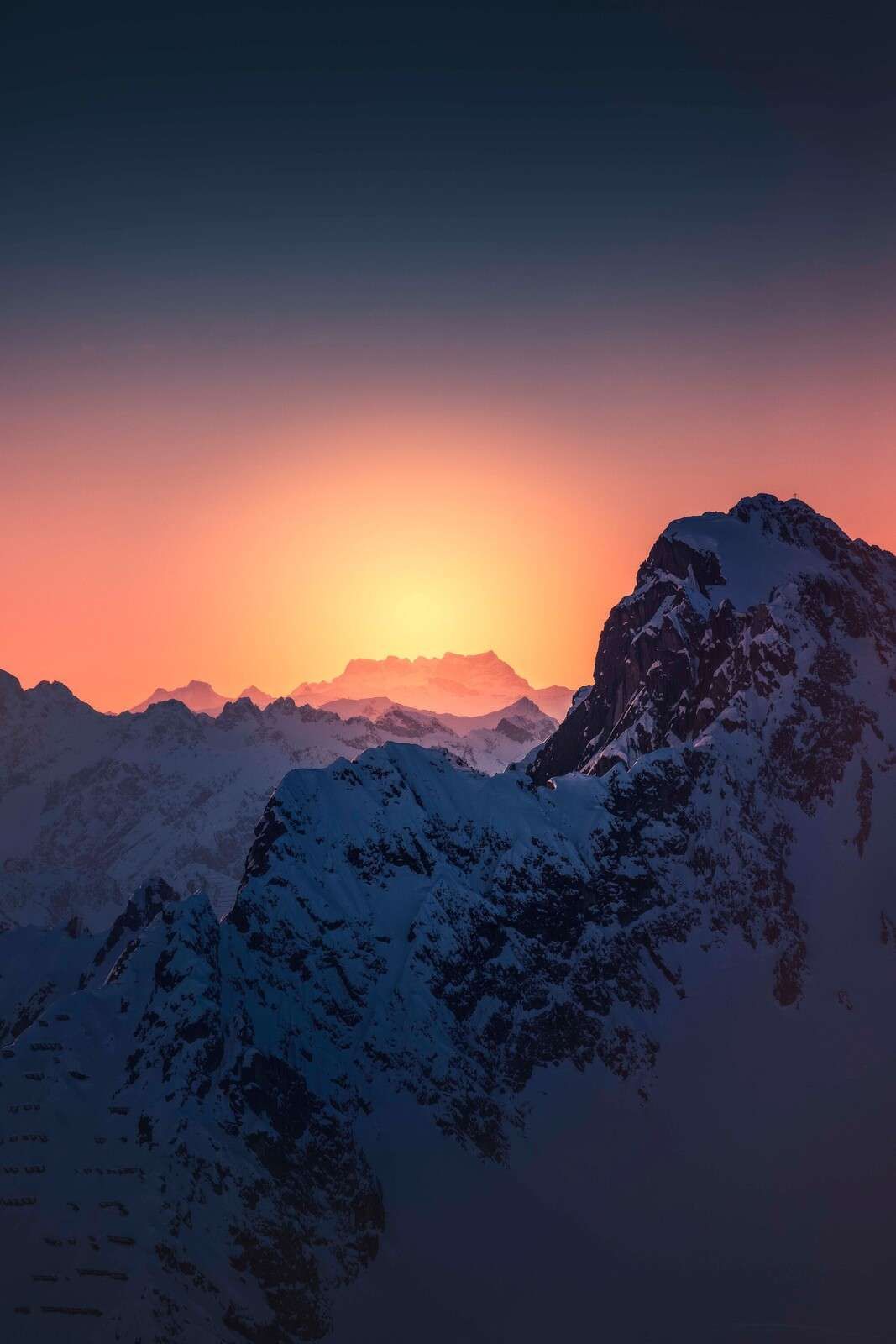 Pico de montaña nevado en un amanecer ardiente.