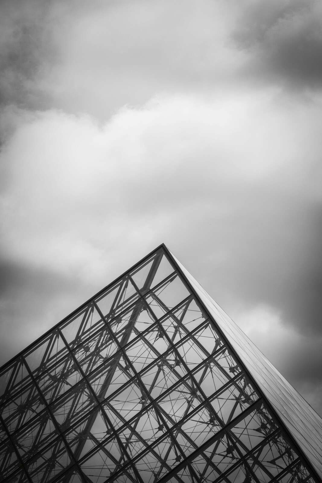 Pirámide de vidrio bajo el cielo nublado.